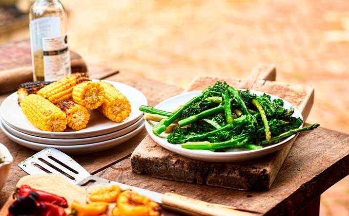 Mazorcas y espárragos sobre una mesa de madera en un asado vegetariano Mazorcas y espárragos sobre una mesa de madera en un asado vegetariano