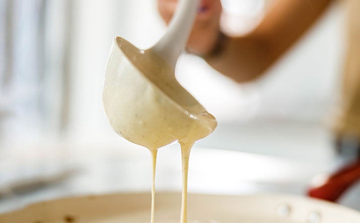 Una mujer preparando pancakes con un cucharón Una mujer preparando pancakes con un cucharón