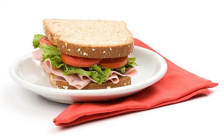 Un sándwich clásico de jamón, lechuga y tomate, uno de los snacks balanceados más populares Un sándwich clásico de jamón, lechuga y tomate, uno de los snacks balanceados más populares