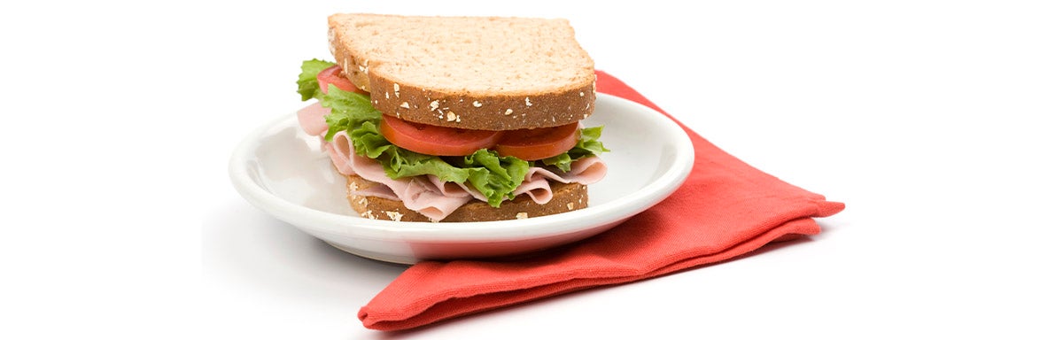 Un sándwich clásico de jamón, lechuga y tomate, uno de los snacks balanceados más populares Un sándwich clásico de jamón, lechuga y tomate, uno de los snacks balanceados más populares