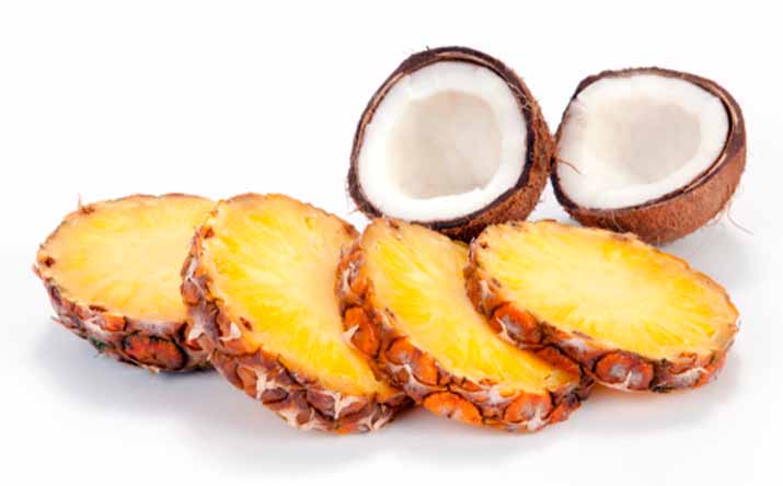 Tajadas de piña y un coco partido por la mitad, dos frutas tropicales Tajadas de piña y un coco partido por la mitad, dos frutas tropicales
