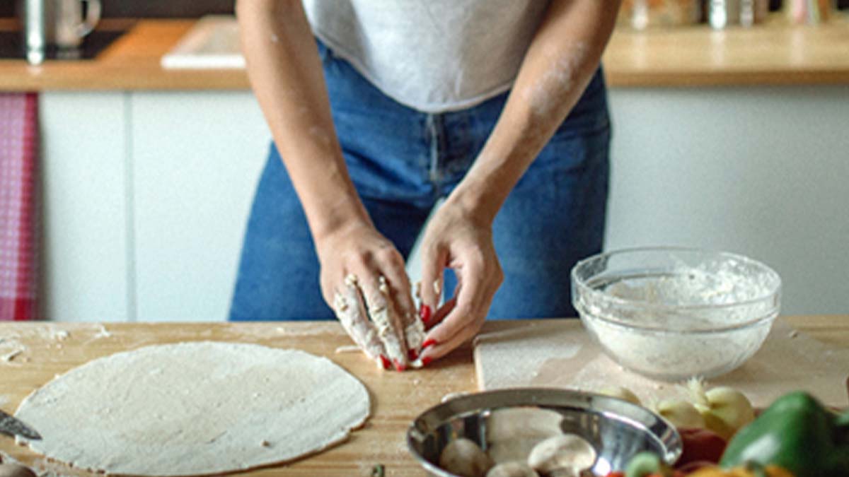 Mujer con utensilios e ingredientes preparando masa para pizza Mujer con utensilios e ingredientes preparando masa para pizza