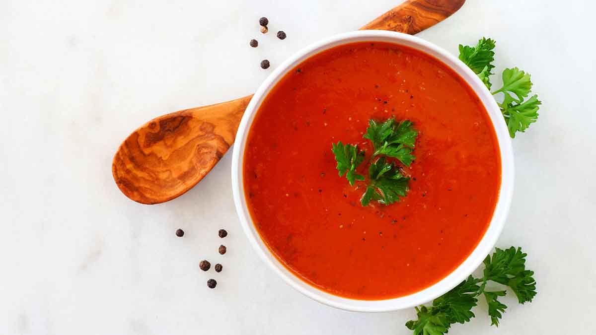 Crema de tomate con perejil, una de las recetas más famosas, servida con una cuchara de madera. Crema de tomate con perejil, una de las recetas más famosas, servida con una cuchara de madera.