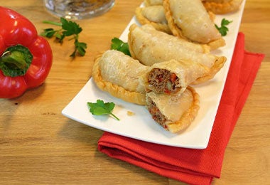 Bandeja de cerámica con varias empanadas de carne y zumaque.