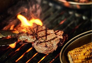 Hombre asando carne a la parrilla en exteriores. Hombre asando carne en parrilla al aire libre