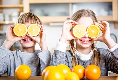 Niños divirtiéndose en la cocina con unas naranjas 