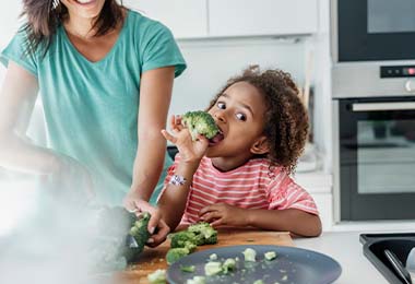 Niño comiendo brócoli en casa	 