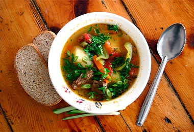 Ajiaco santafereño servido con pan y vegetales frescos.