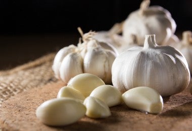 Ajos y cascos de ajo sobre una tabla de picar para la langosta al ajillo.