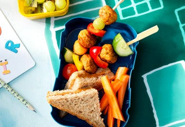 Lonchera para alimentación escolar con sándwich integral, brochetas de pollo y frutas