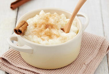 Arroz con leche, clavos de olor y canela acompañado de una cucharada de madera.