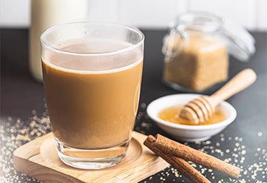 Bebida caliente con leche, café, miel y azúcar morena sobre una superficie negra