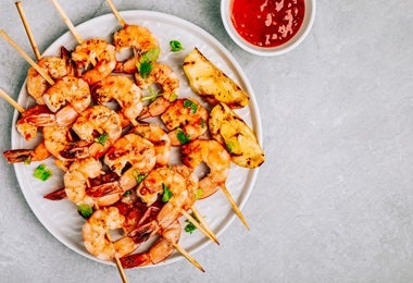 Brocheta de gambas y camarones con salsa de tomate en toma cenital.