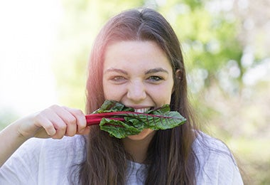 Mujer en busca de alimentos sostenibles muerde hojas de espinaca