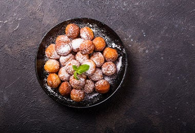 Plato de buñuelos espolvoreados para repartir como entrada de comida en fiesta.