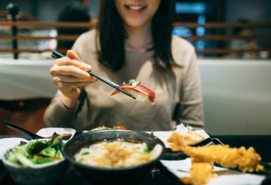 Mujer degustas sushi de calamar de tubo pequeño, otro de los tipos de calamar.