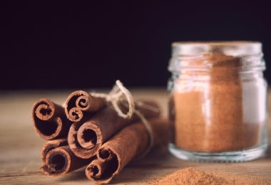 Racimo de clavos de canela junto a una piza y un recipiente de canela en polvo para mazamorra morada.