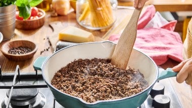 Cocción de carne molida en sartén mientras se revuelve, elemento esencial para el huevo escocés.