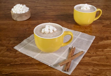 Tazas de chocolate caliente con malvaviscos, bebida clásica para disfrutar mientras ves películas de Navidad.