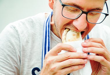 Un hombre comiendo una empanada tucumeña, una clase de empanada argentina. 