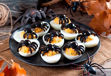 Huevos arácnidos sobre un plato negro para una fiesta de Halloween