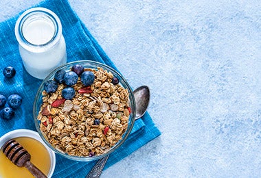 Tazón con granola, fruta, leche y miel en desayuno continental  