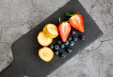 Tabla con fresas, arándanos y bananos en desayuno continental  