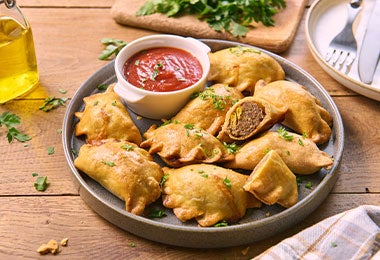 Bandeja de empanadas de carne molida con salsa de ají para cumpleaños.