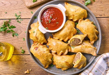 Plato de empanadas con un dip de tomate, un frito similar a los buñuelos de yuca