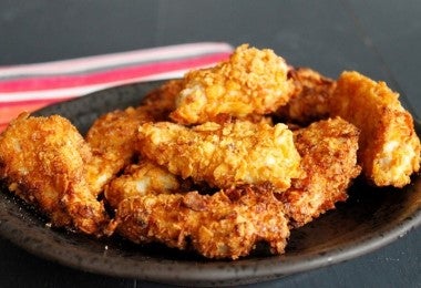 Piezas de pollo empanizado con harina de tapioca sobre un plato.