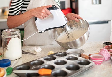 Mujer mezclando masa de muffins frente a una mesa con moldes de silicona.