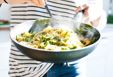 Fideos de arroz con verduras salteadas en una sartén.