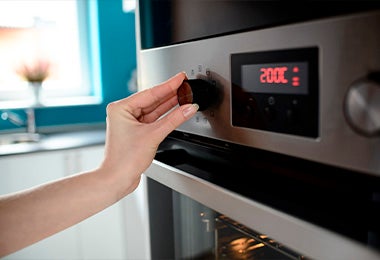 Mujer ajustado temperatura en horno para hacer galletas fáciles