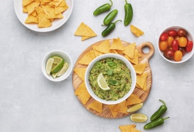 Bowl de guacamole con totopos, tomatillos, chile y limón para comer con anchoas.