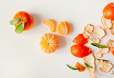 Mandarina en gajos y cáscaras y hojas de mandarina