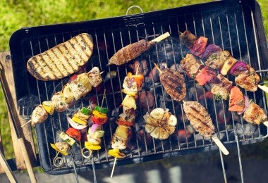 Parrillada con brochetas de mollejas de res y otros cortes asándose