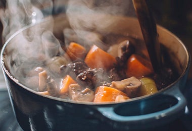 Olla de acero cocinando una sopa de vegetales en su interior.