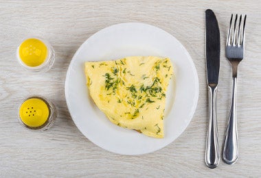 Omelette con hierbas, un salero y cubiertos, un desayuno con alta carga de nutrientes