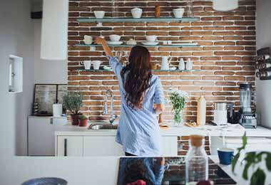 Mujer ordenando su alacena con tazas y vasos