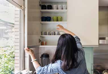 Una mujer ordenando los estantes de su cocina 