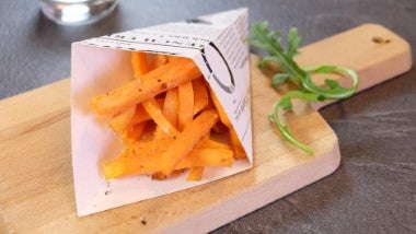 Porción de papas fritas de camote sobre una tabla de picar de madera.