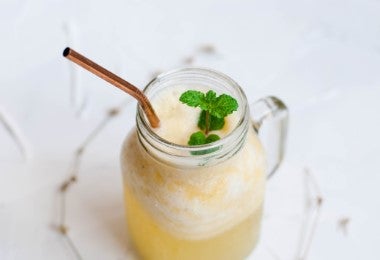 Smoothie de piña y coco con pitillo y en mini jarrón de vidrio.