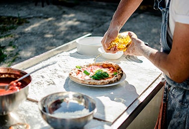 Hombre rociando aceite de oliva en pizza