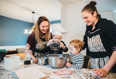 Familia preparando receta con niños y usando elementos de seguridad.