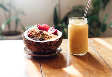 Smoothie de mandarina con maracuyá y un bowl de fruta servido en cáscara de coco