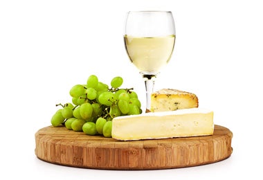 Tabla de quesos, con uvas verdes y bebida.