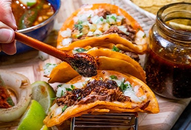 Tacos de birria con clavos de olor, cebolla y cilantro.