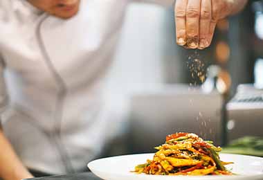 Un chef añadiendo SAZONADOR NATURÍSIMO MAGGI® a un plato