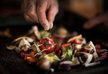 Una persona añadiendo un tipo de sal a una ensalada.