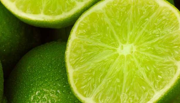 Un limón, uno de los cítricos más usados, partido por la mitad, encima de más limones. 